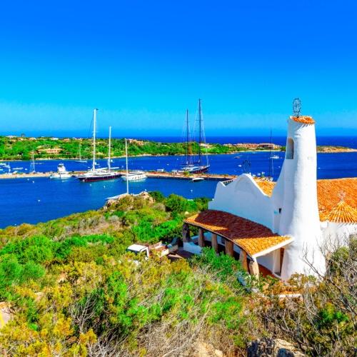 Het witte kerkje Stella Maris met daar achter de imposante jachthaven van Porto Cervo