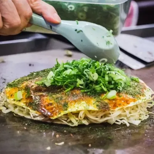 Een Japanse pannenkoek gevuld met kool en vlees of garnalen