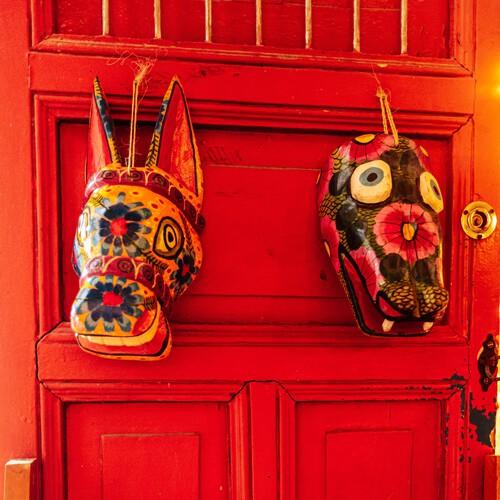 Gekleurde maskers hangend aan rode deur, Mérida