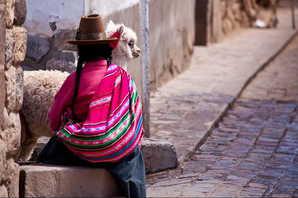 Vrouw in traditionele kleding met lama in Cuzco